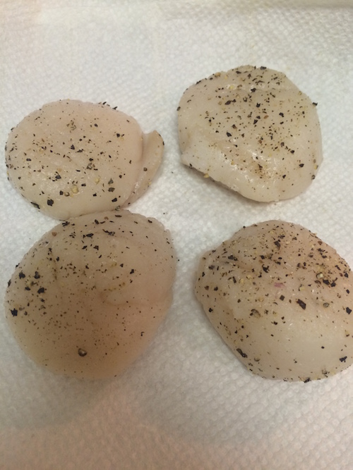 Prepping scallops on paper towels with seasoning
